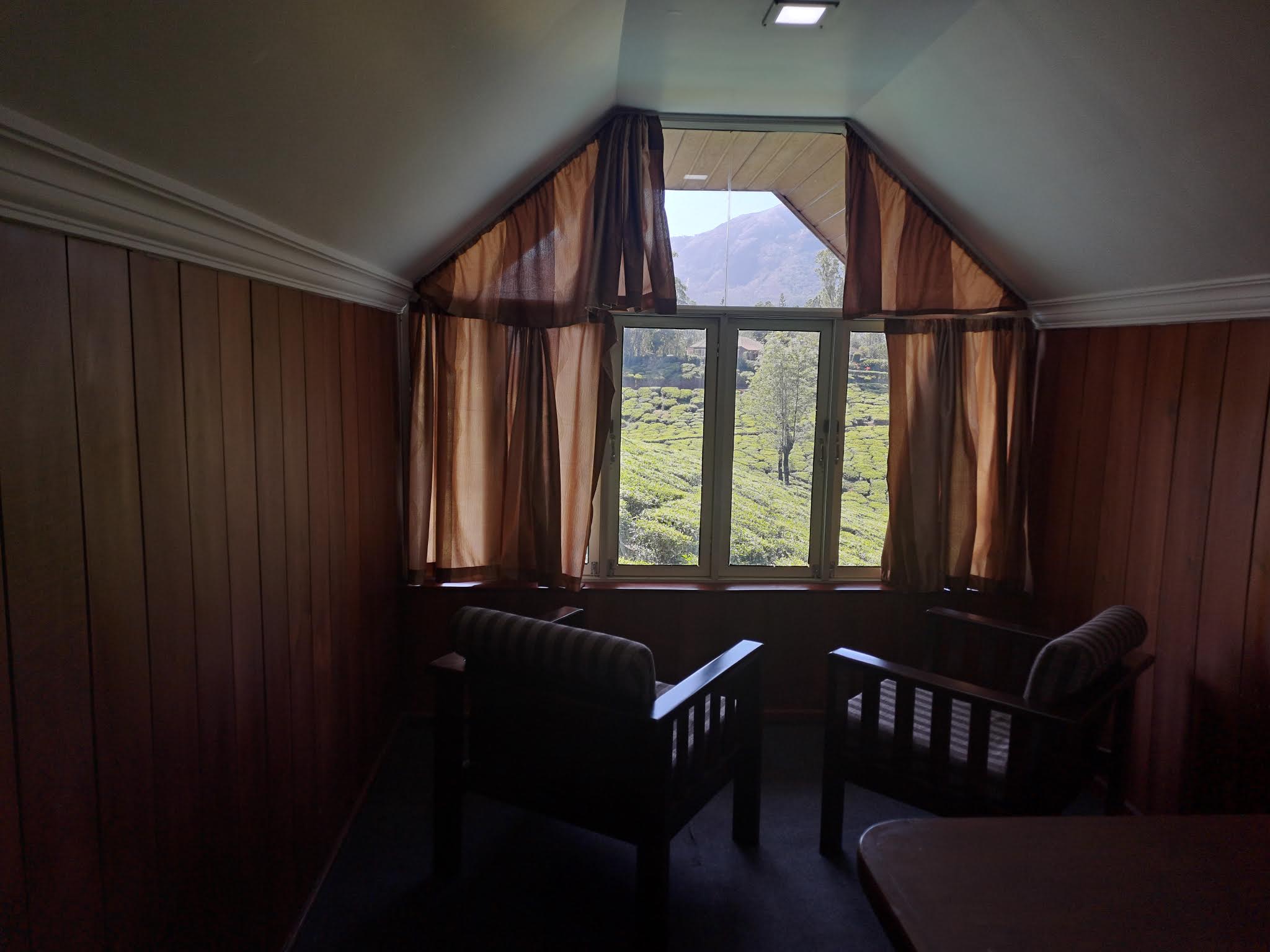 View looking out from warm wooden room into green tea plantation hills